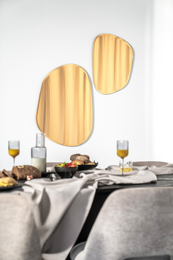 Twee Hotel Chique spiegels met organische vorm, zonder lijst met amberkleurig glas. De spiegel hebben twee maten en hangen in een eetkamer.