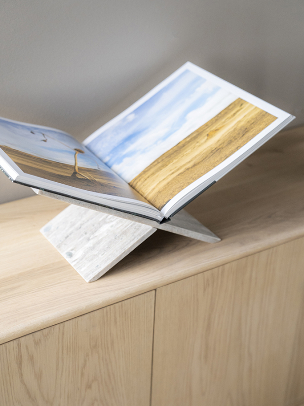 De boekenstandaard is gemaakt van marmer materiaal en heeft een eenvoudig, modern ontwerp in de vorm van een kruis. Twee planken zijn schuin op elkaar geplaatst om een stabiele, X-vormige basis te creëren waarop boeken kunnen worden geplaatst. De natuurlijke marmerpatronen geven de boekenstandaard een elegante en luxe uitstraling, waardoor het een functioneel en decoratief element is voor elk interieur.