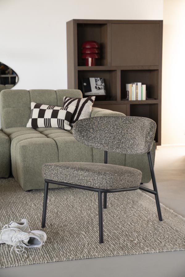 Fauteuil Jari – groen Grijsgroene fauteuil in woonkamer met groene bank en beige vloerkleed.
