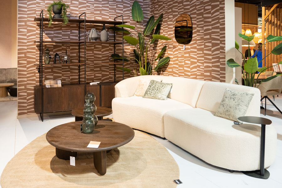 Beige bank met ronde houten salontafel en hoge wandkast in retro woonstijl tijdens Maison & Objet.